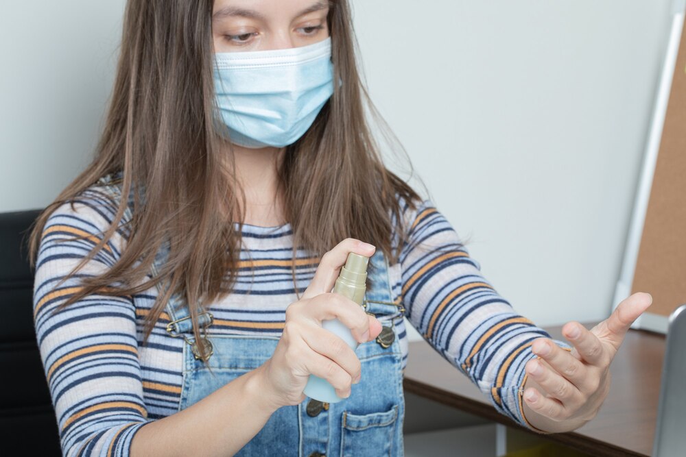 Female employee using basic sanitiziring tools to keep the office sterile