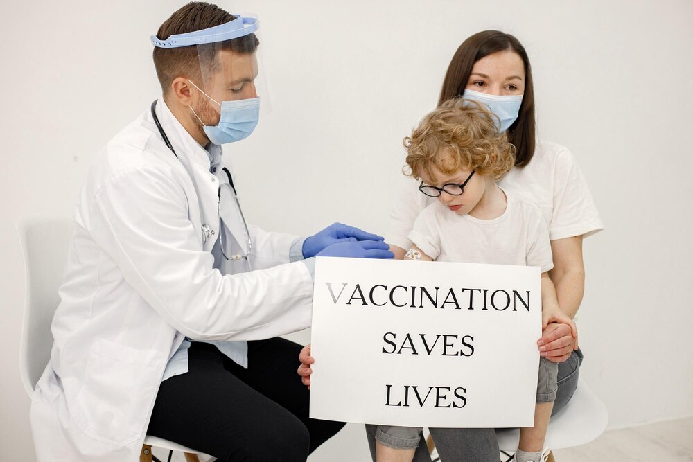 Little boy mother and male doctor holding a poster about vaccination